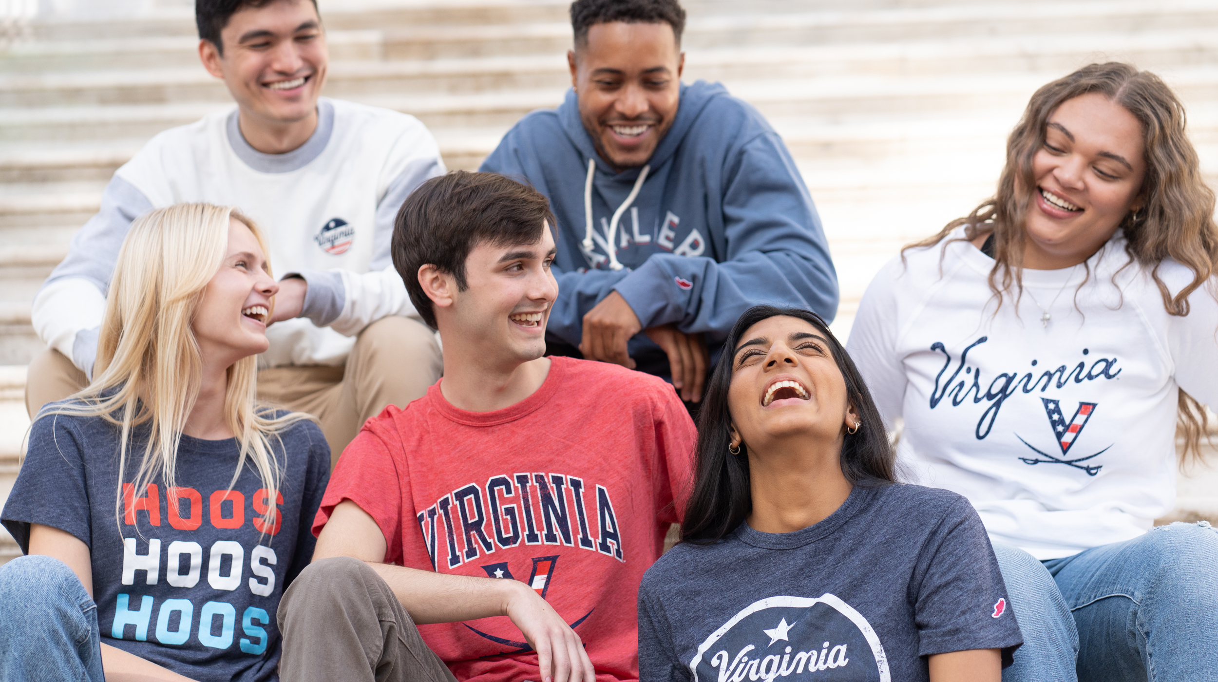A group of people sitting on the Rotunda steps in Red, White and Hoo gear
